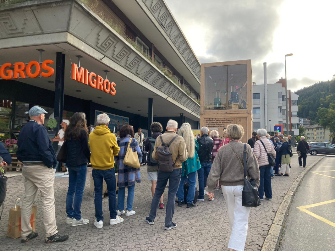 Viele Menschen stehen Schlange, um einen Einkaufstrolley zu bekommen.